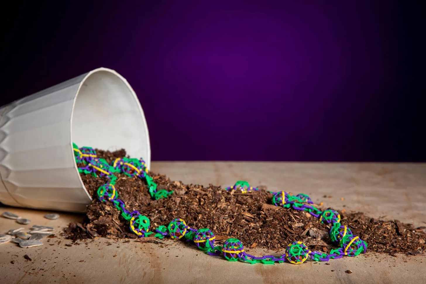 Purple, yellow, and green beads falling out of a cup of dirt