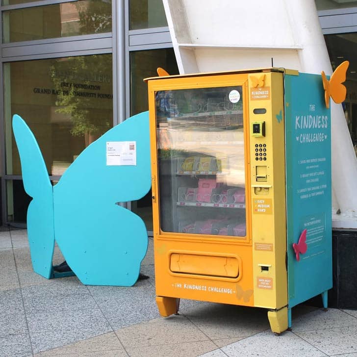 Yellow and teal vending machine with butterfly cutouts attached to it