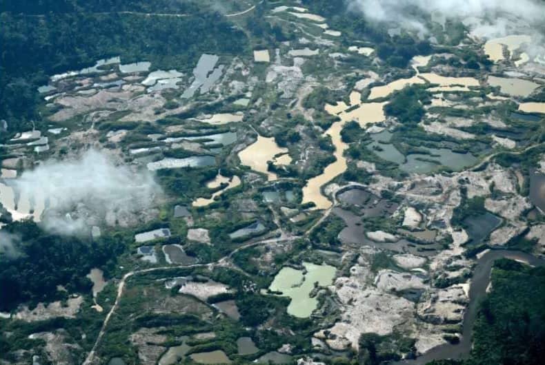 Aerial photo of a forested area broken up by parcels of water, mining