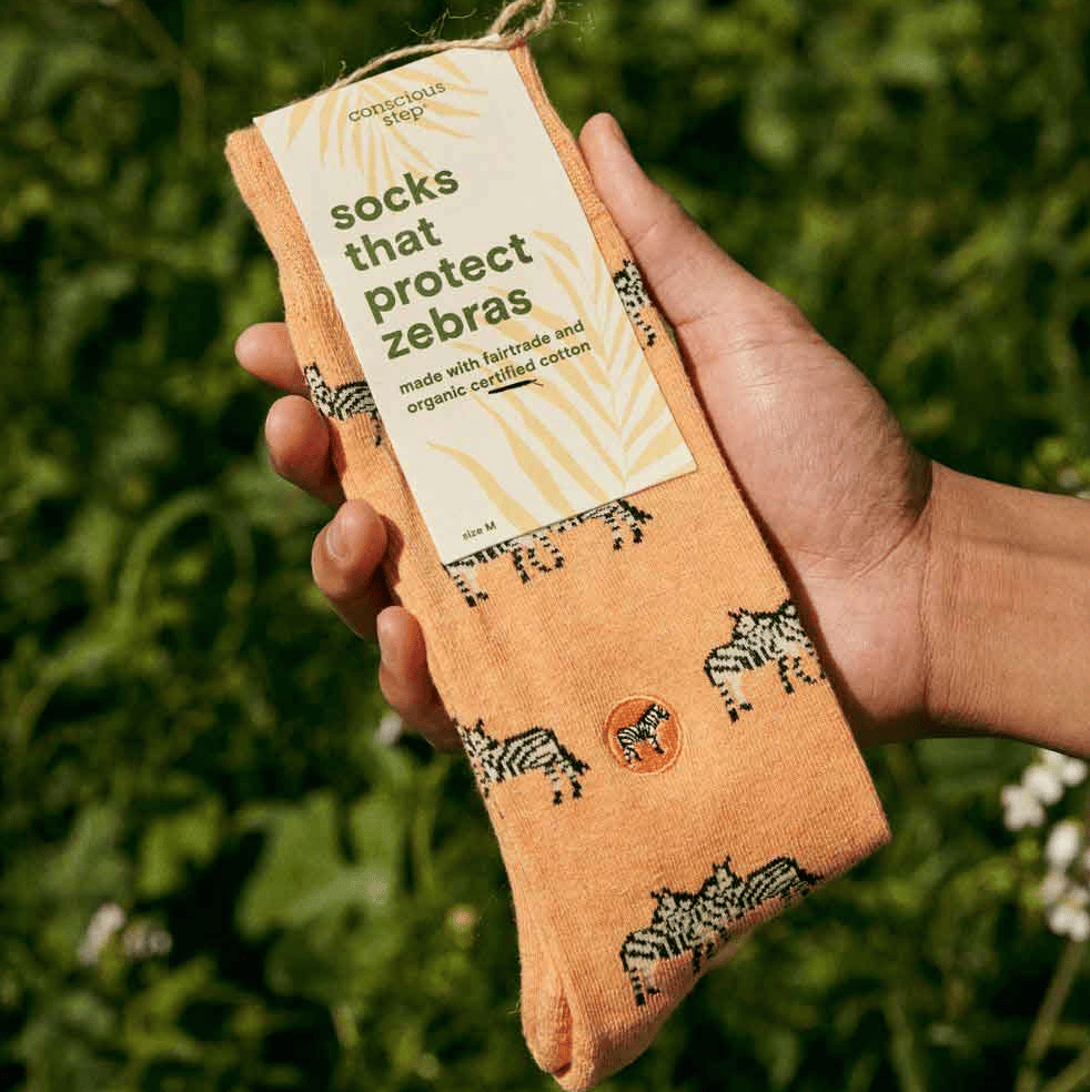 Hand holding pair of socks with "socks that protect zebras" label