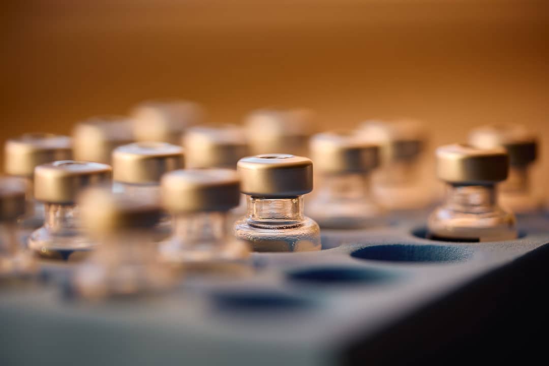 Multiple small glass vials with gold caps arranged on a surface, with shallow depth of field focusing on the nearest vial.