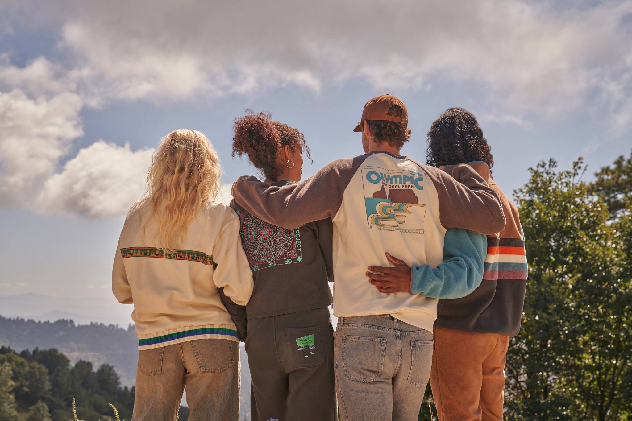 Four people standing with their backs to the camera looking into the distance wearing Parks Project gear