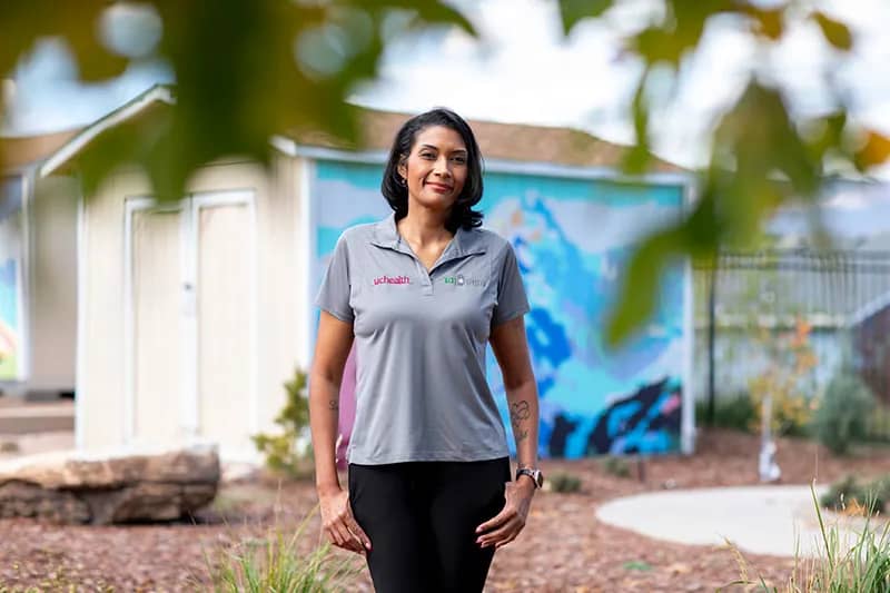A woman in a grey polo shirt standing in front of a painted shed