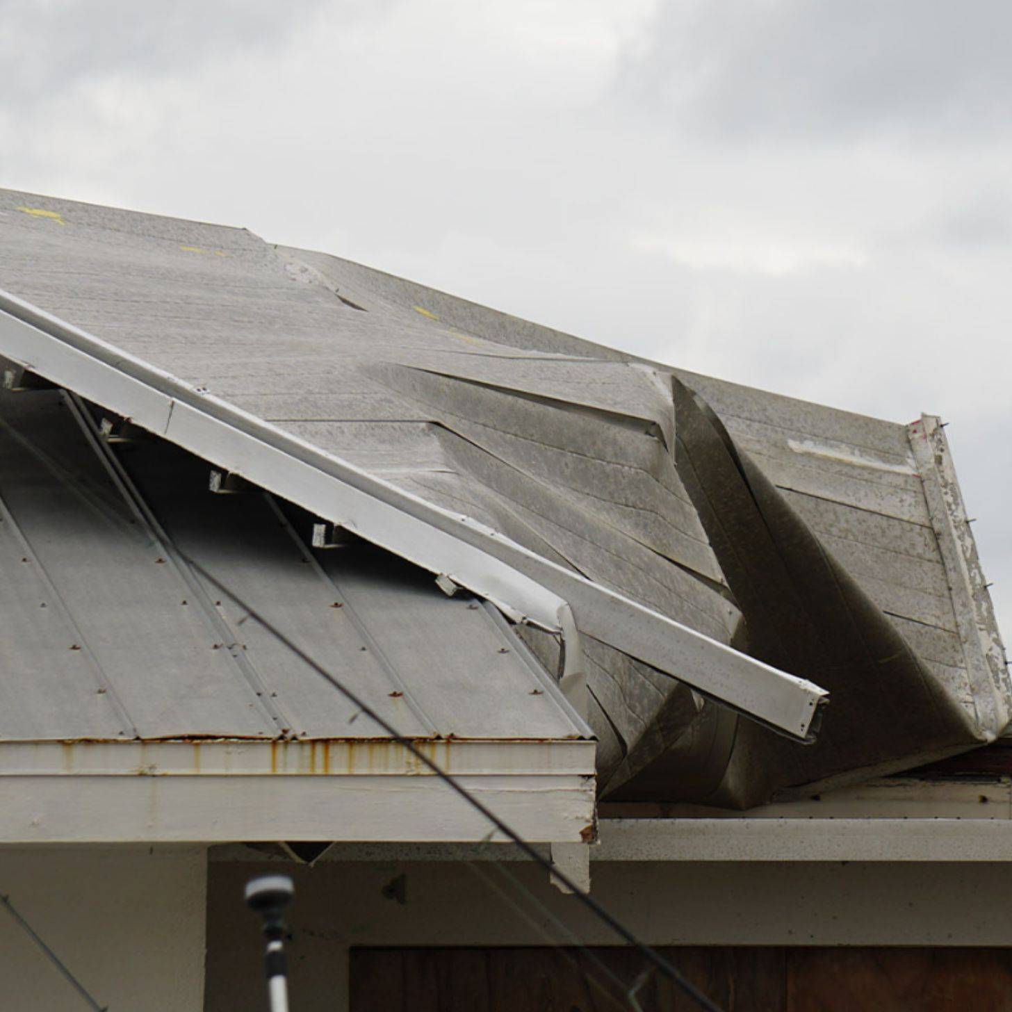 Close-up of a corner of a roof that's been bent and busted