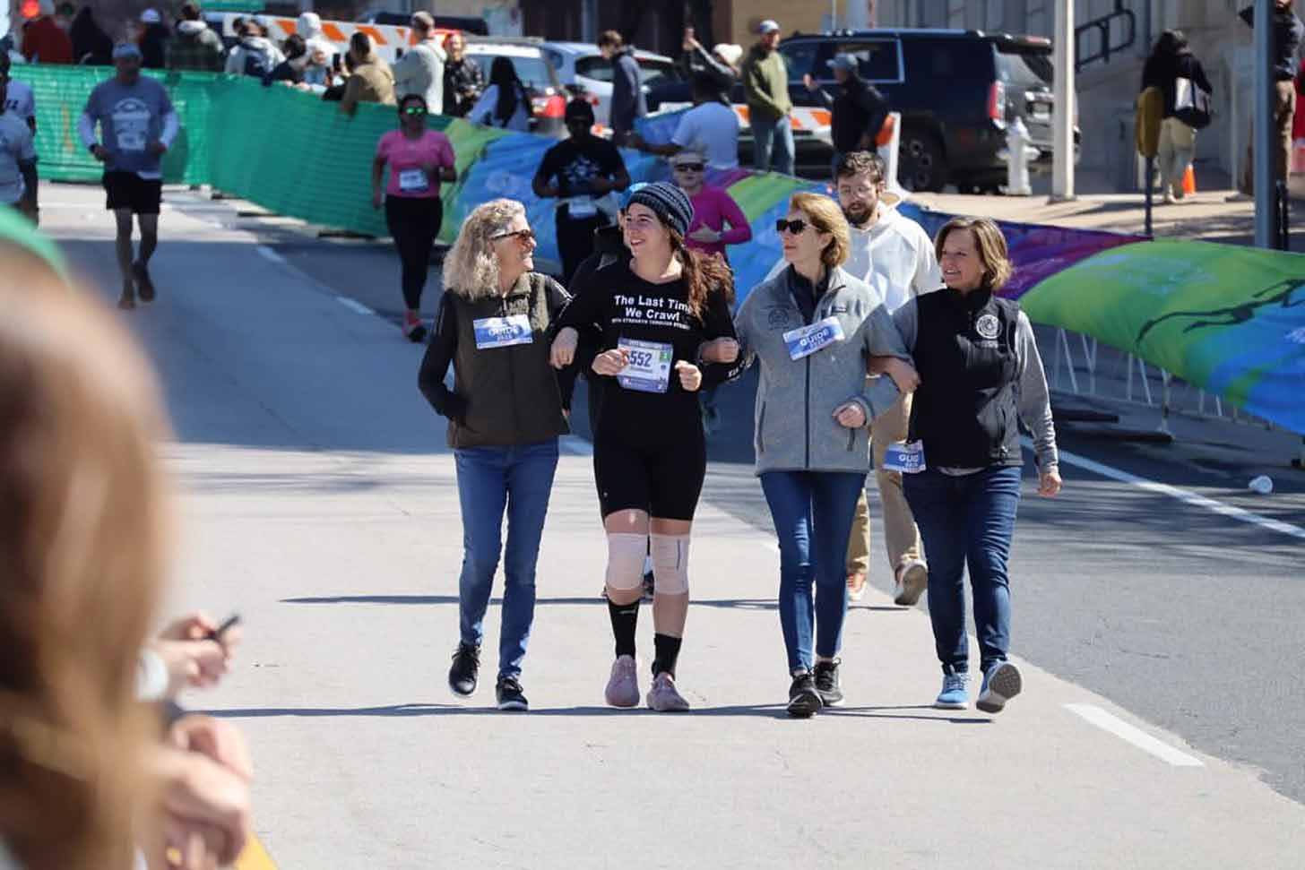 Four people arm in arm walking in a race