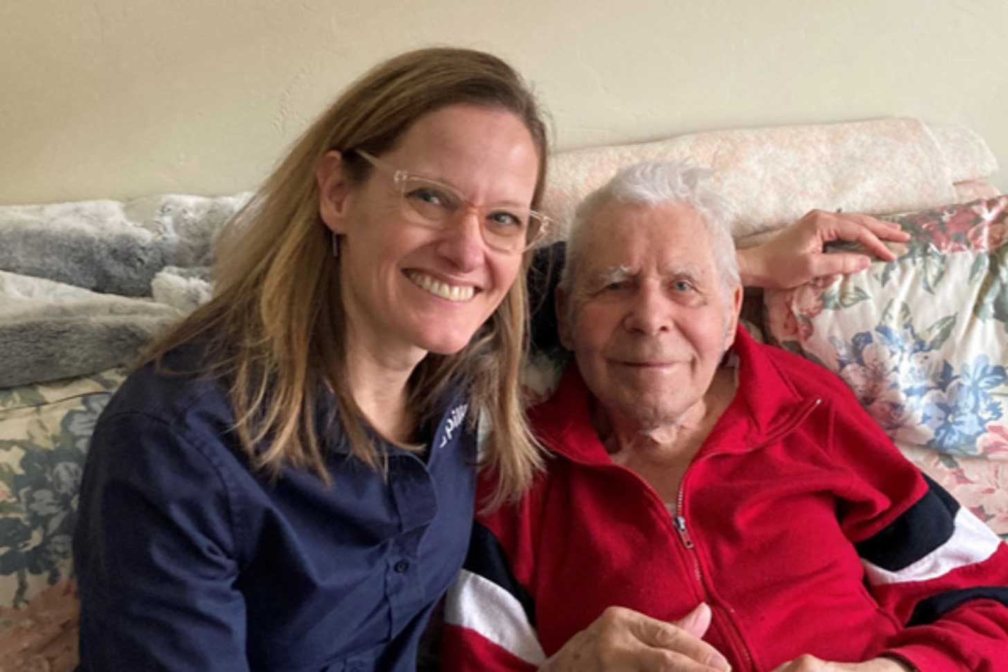 A woman sitting next to an older man on a floral sofa