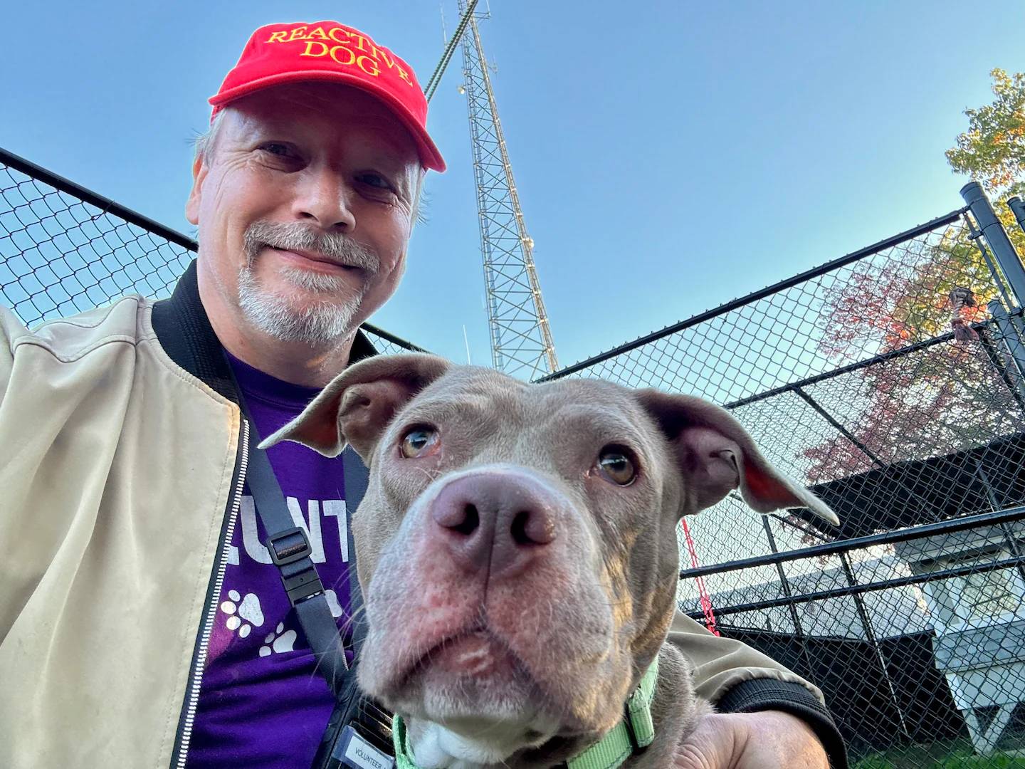 Selfie of a man and dog, man is wearing a red "reactive dog" hat