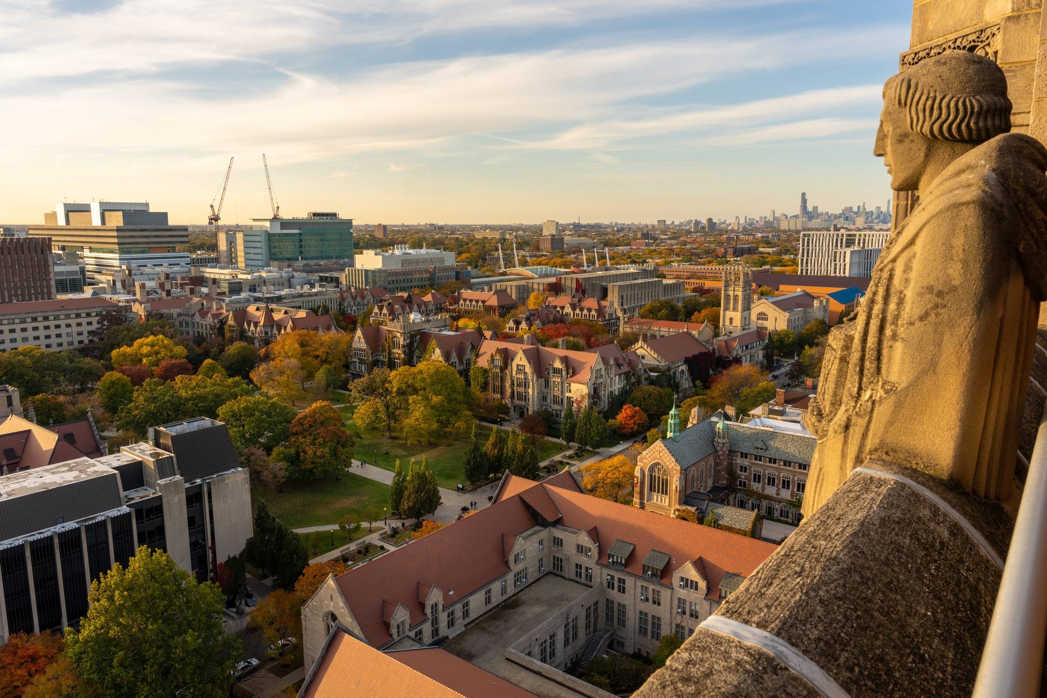 Bird's-eye view of the university campus, a yellow sunset glow is over buildings, and the city is in the background