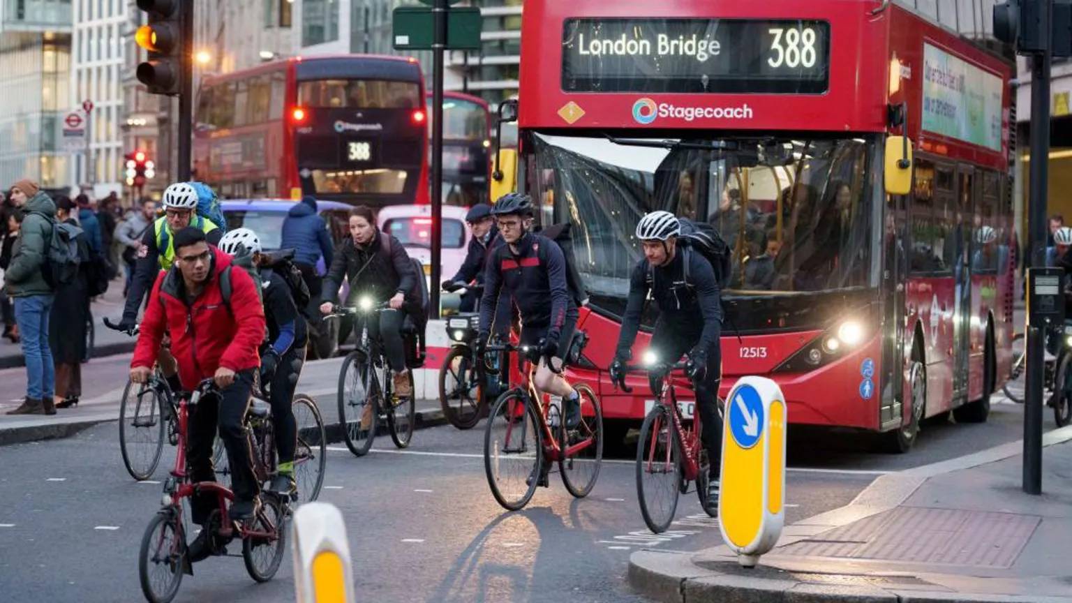 Cyclists in front of a double-decker red bus