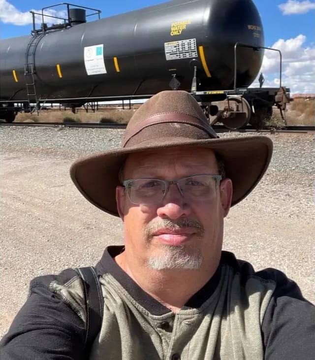 A selfie of Andrew Halter standing in front of a large train tank for water