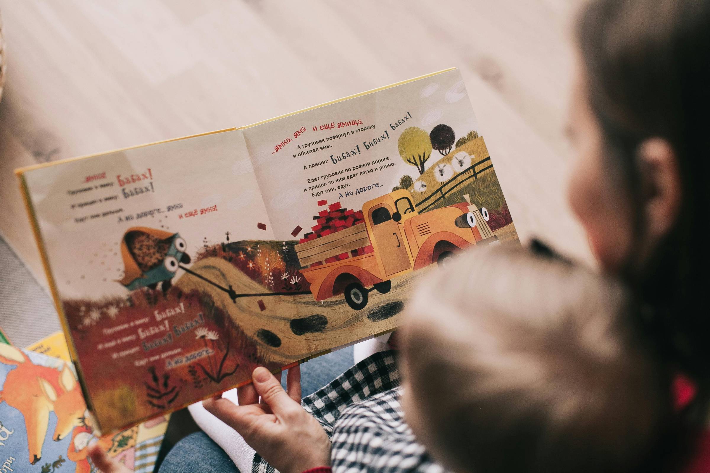 Overhead photo of a person reading a book to a child in their lap