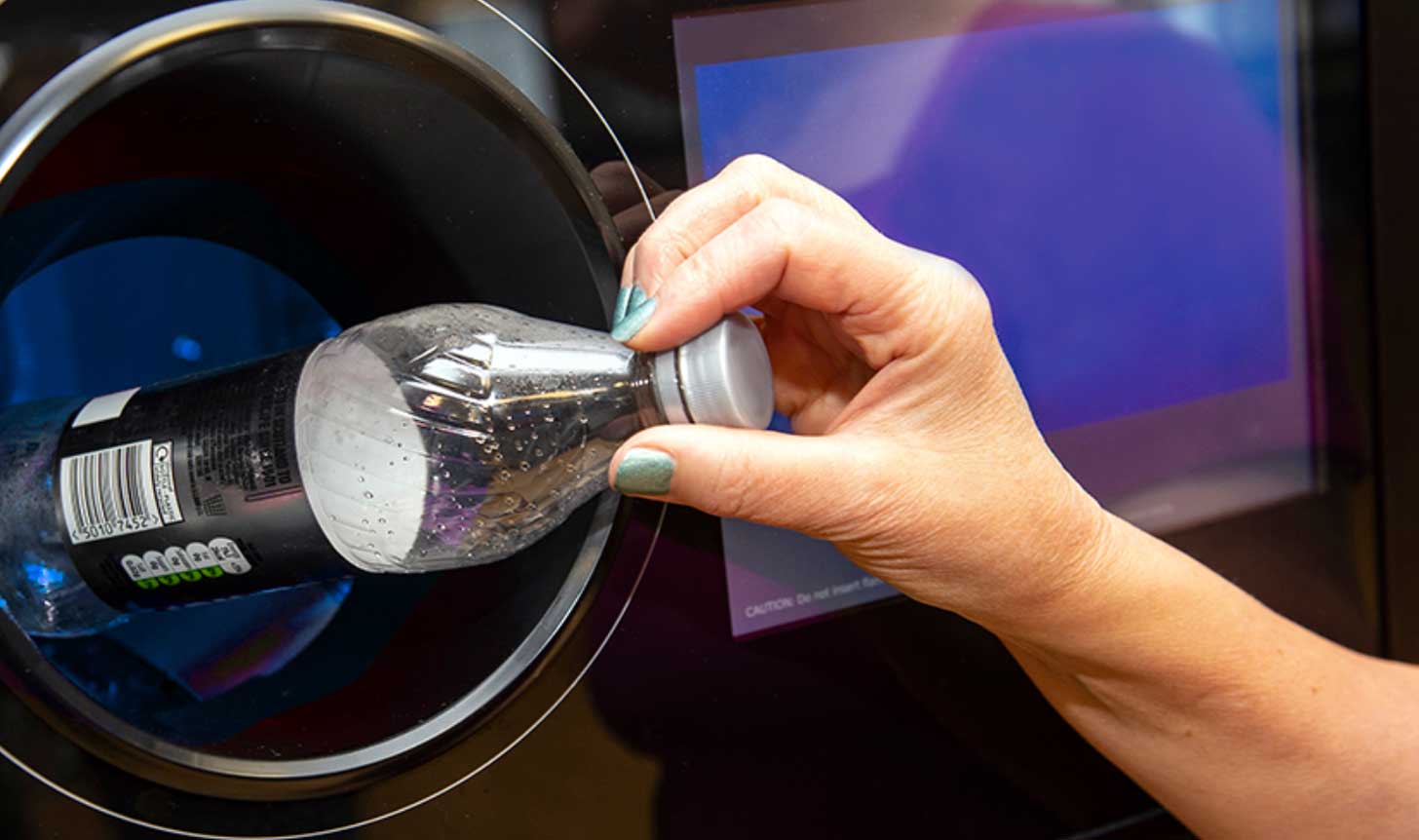 Hand putting a plastic bottle into a collection bin