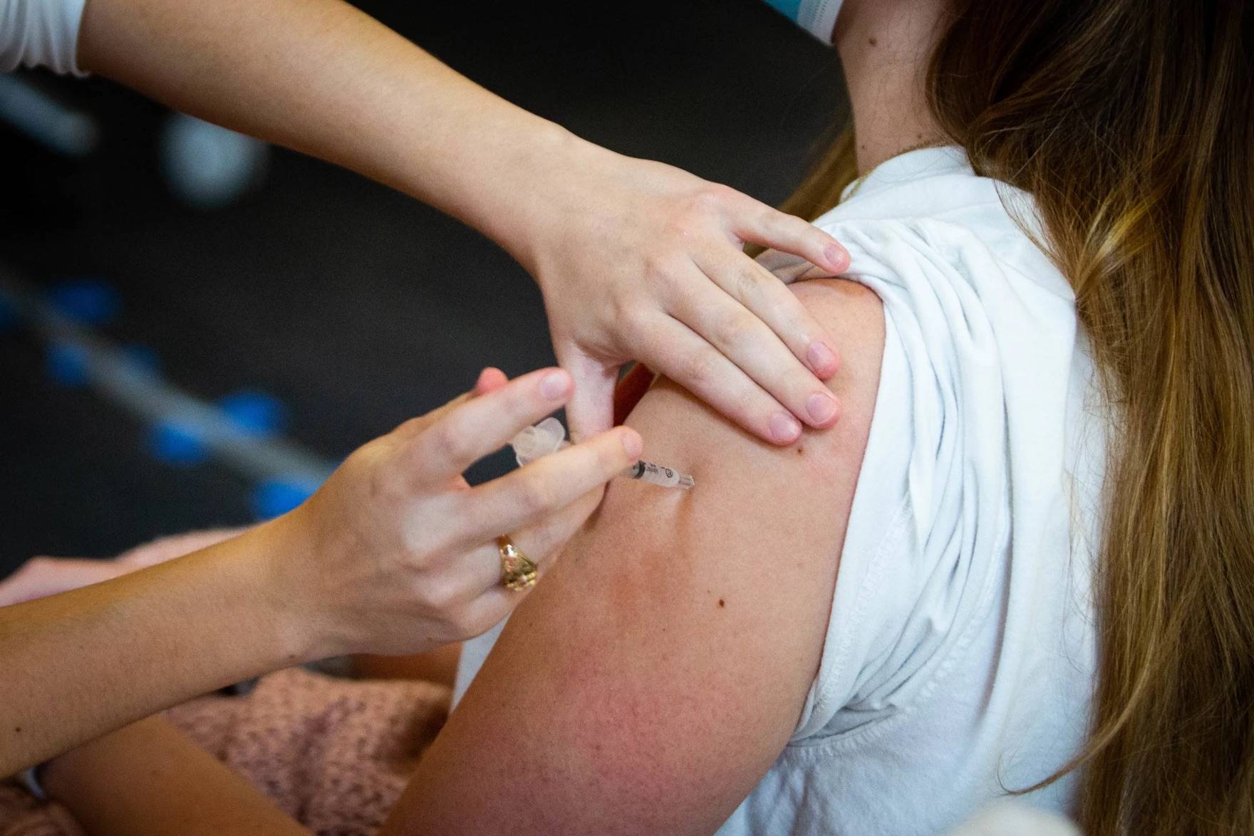 Close-up photo of a person with their sleeve rolled up getting a shot in their left arm
