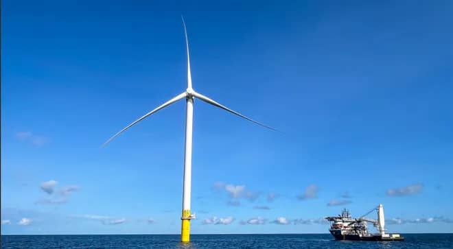 Wind turbine surrounded by water, a ship is installing another next to it