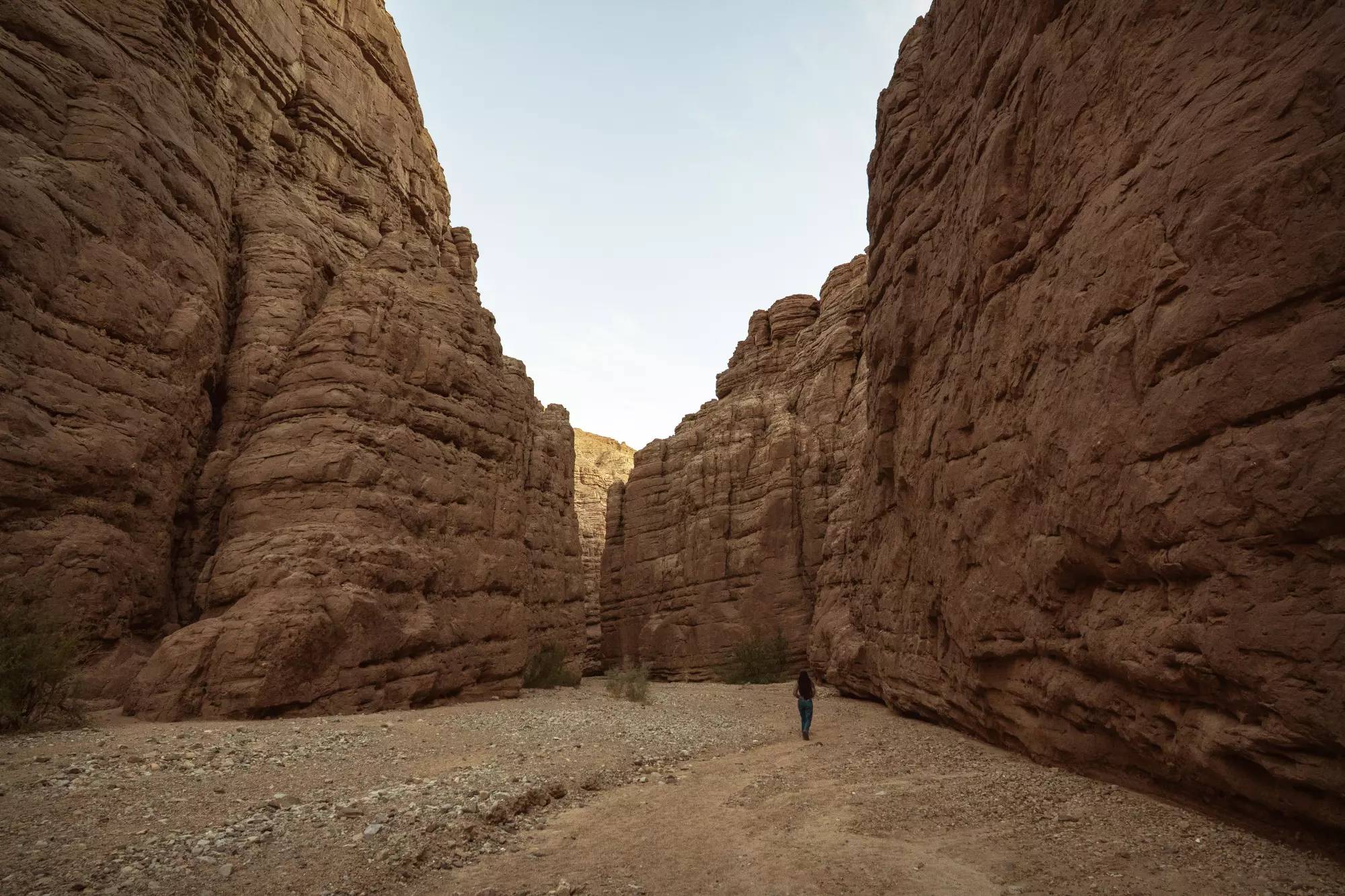 A person walking between two massive towering rock formations