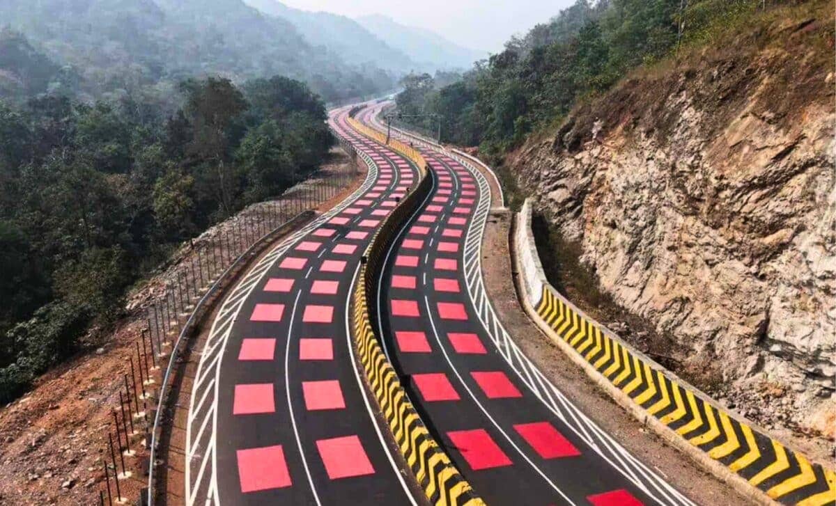 A roadway winding through a mountainous area, the black road is painted with large red squares