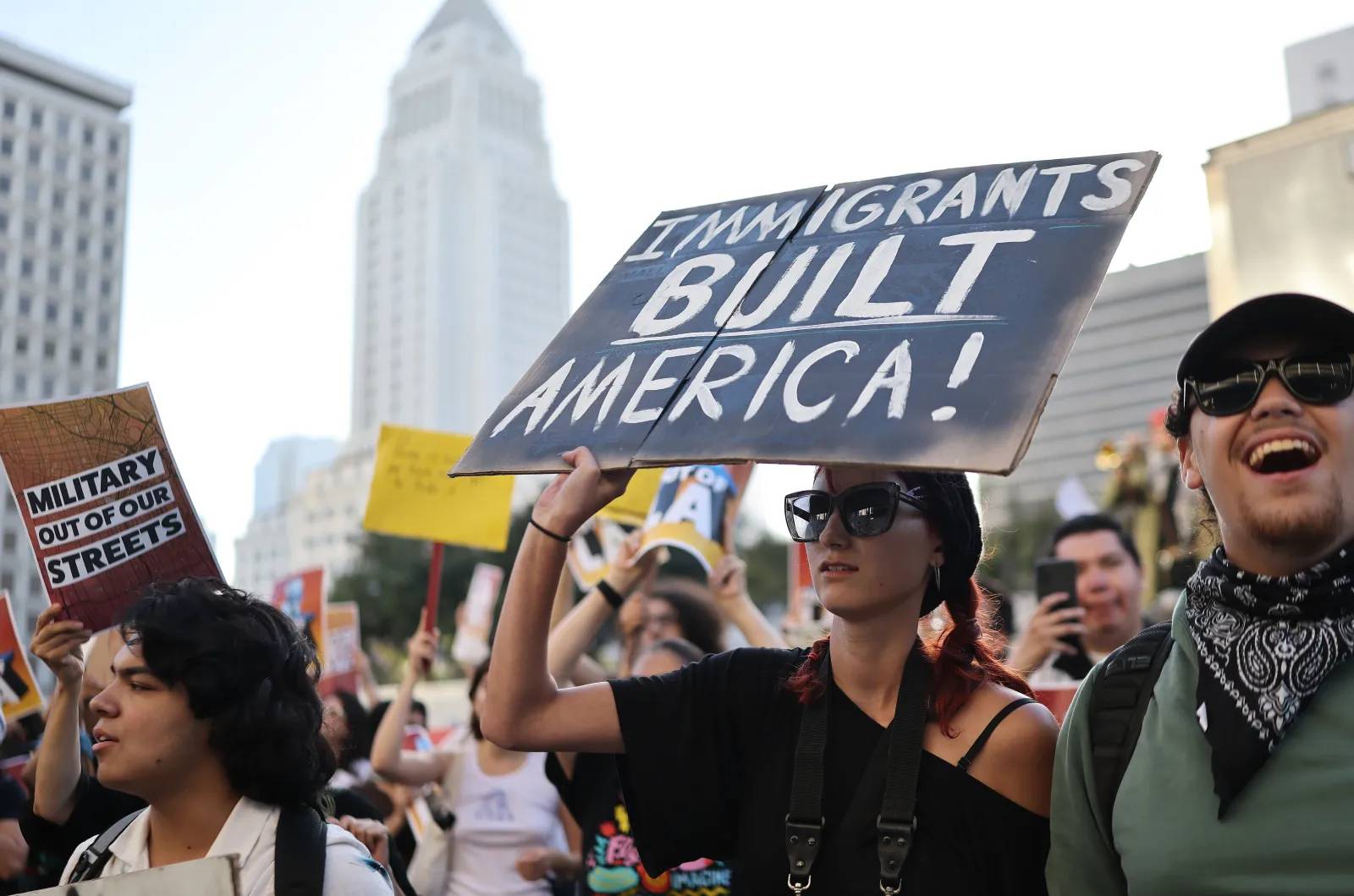 A person holding a protest sign that says "Immigrants Built America!"