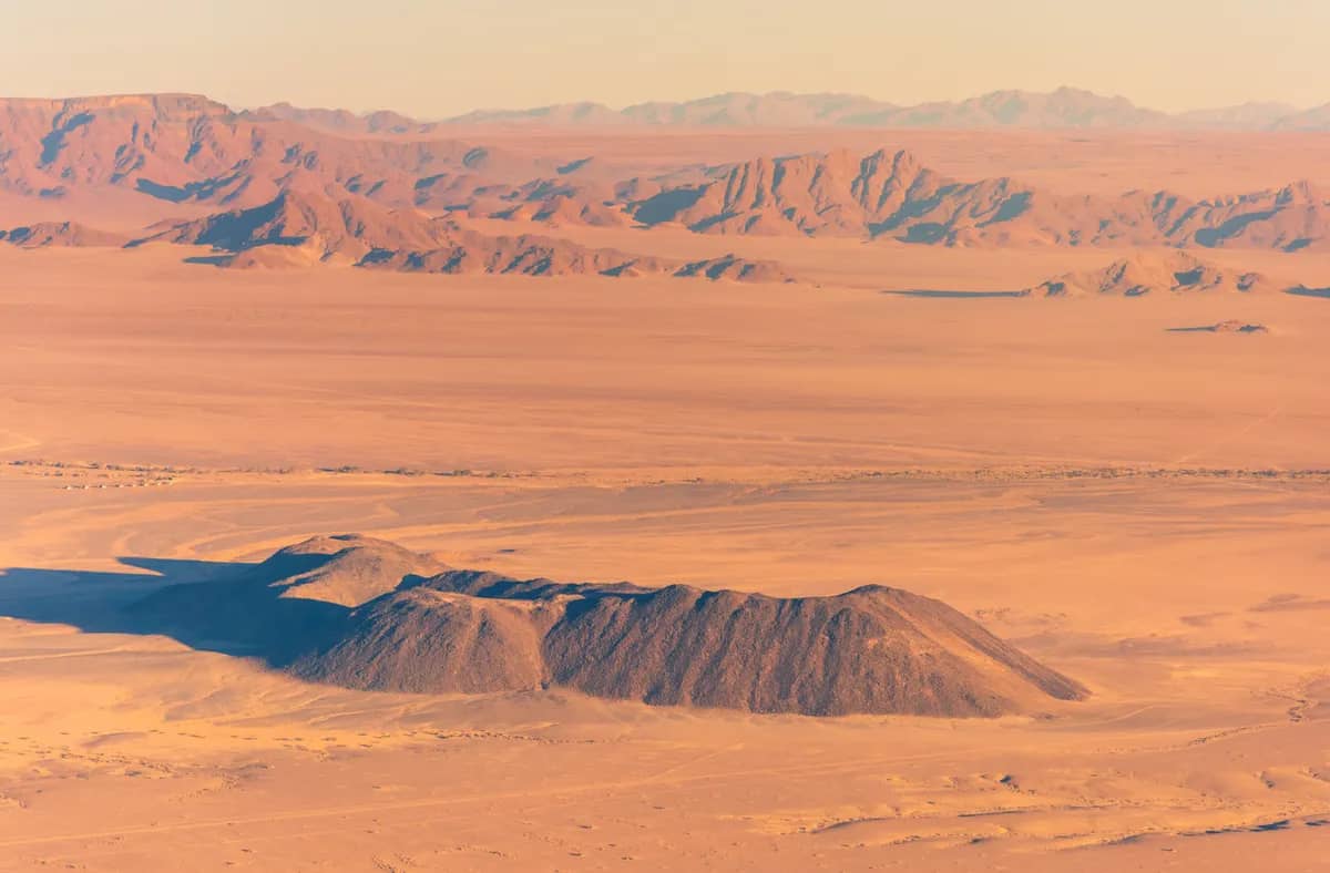 A slightly overhead, wide photo of a orange-red colored desert