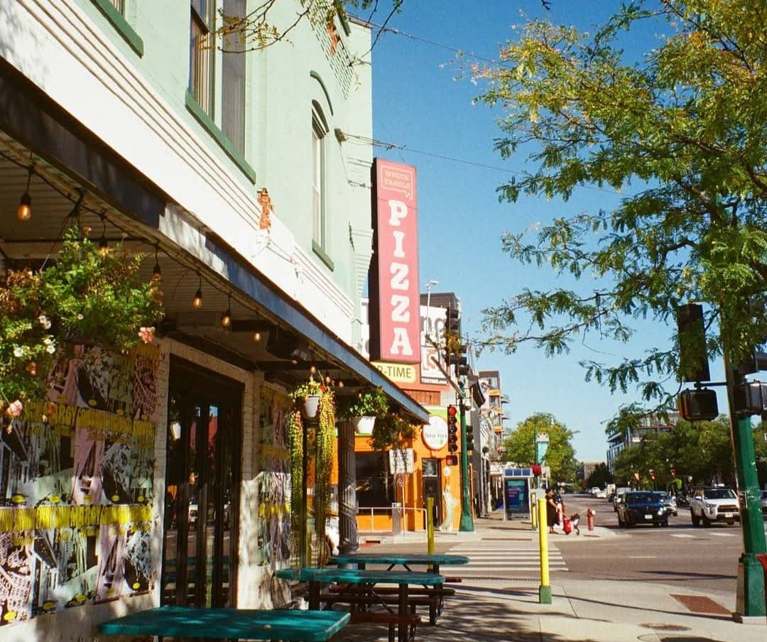 Exterior of a pizza shop on a street filled with shops