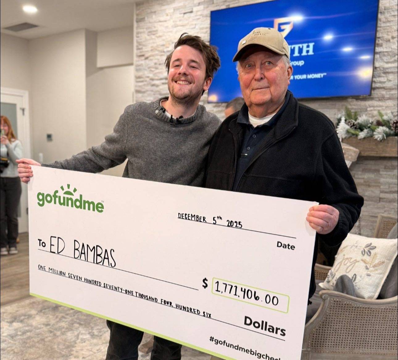 Ed Bambas and Samuel Weidenhofer holding a big "GoFundMe" check for $1,771,406.00