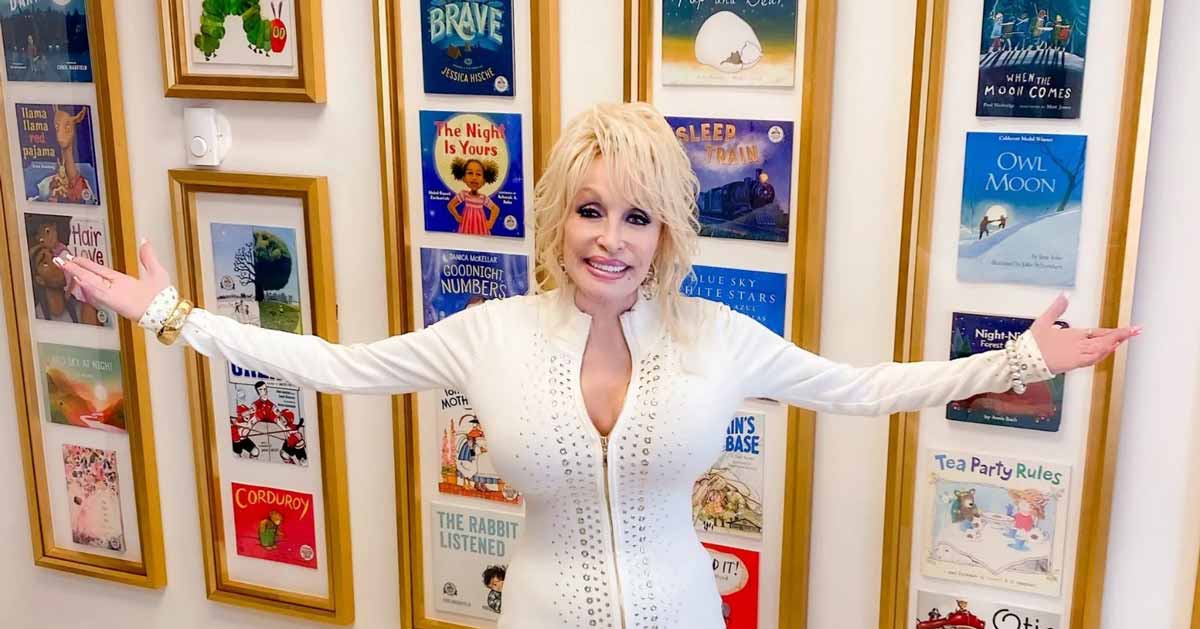 Dolly Parton standing in front of a wall filled with frames of book covers