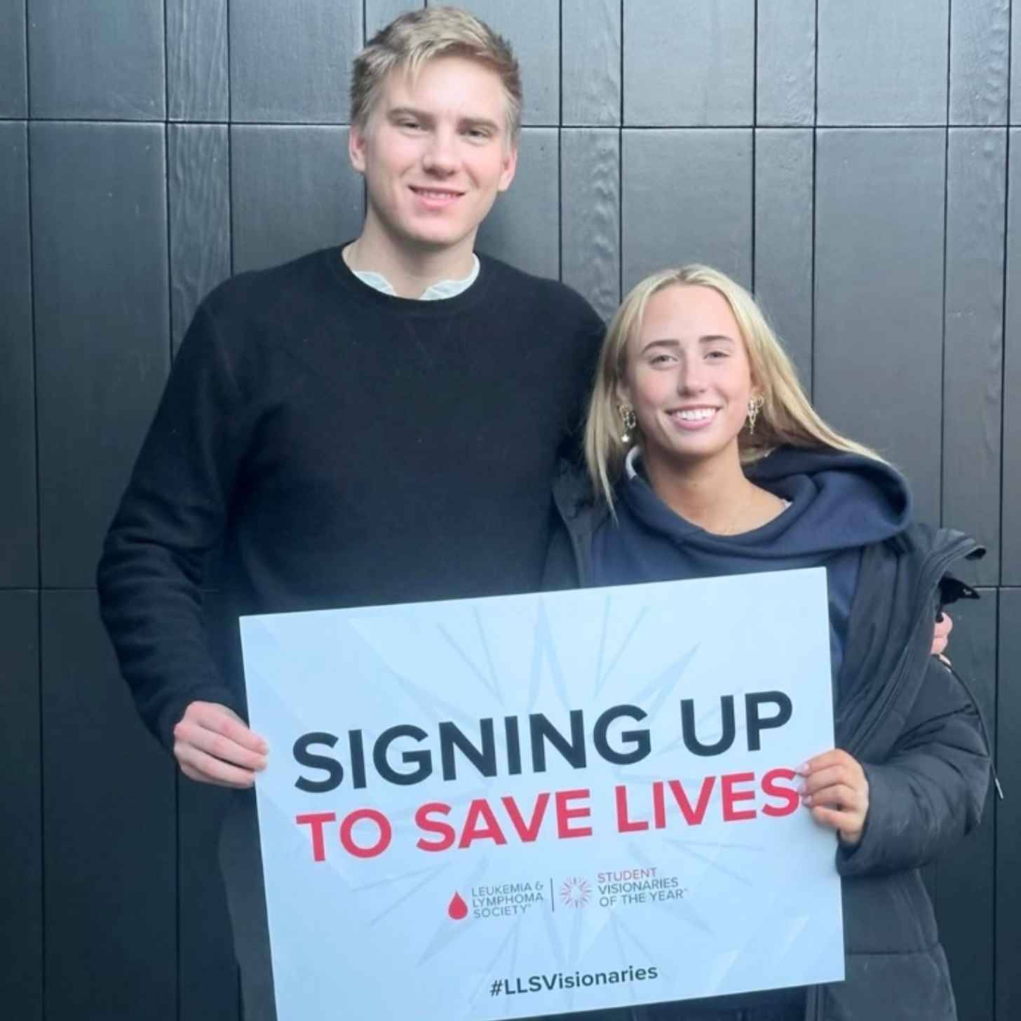 Two teenagers holding a sign that says "Signing up to save lives"