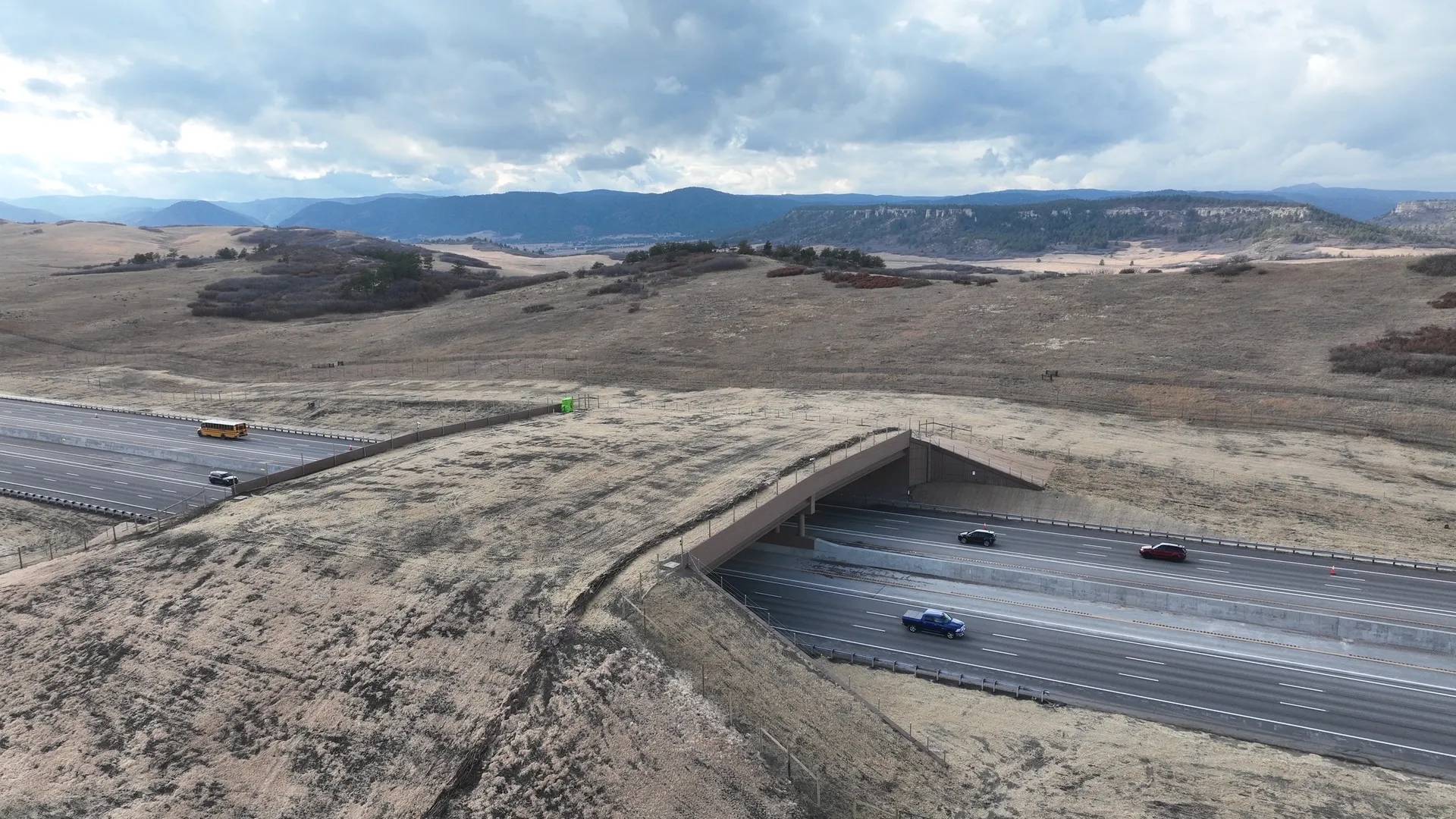 Aerial photo of a bridge over a highway, the bridge is covered in grass