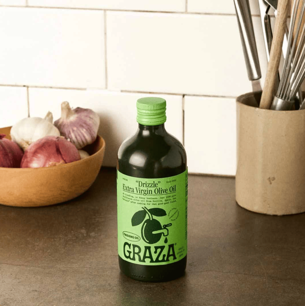 Green bottle of Graza olive oil on a countertop