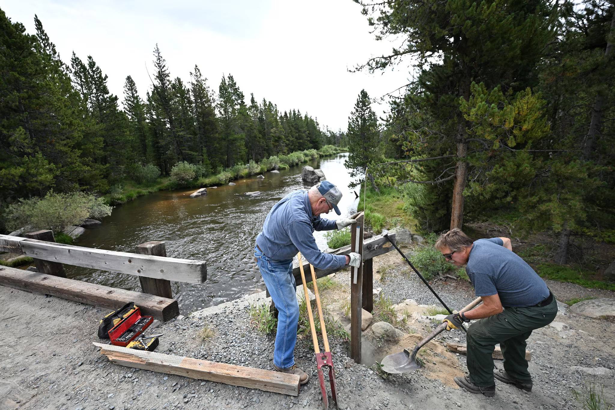 Two people fixing a post near a creek
