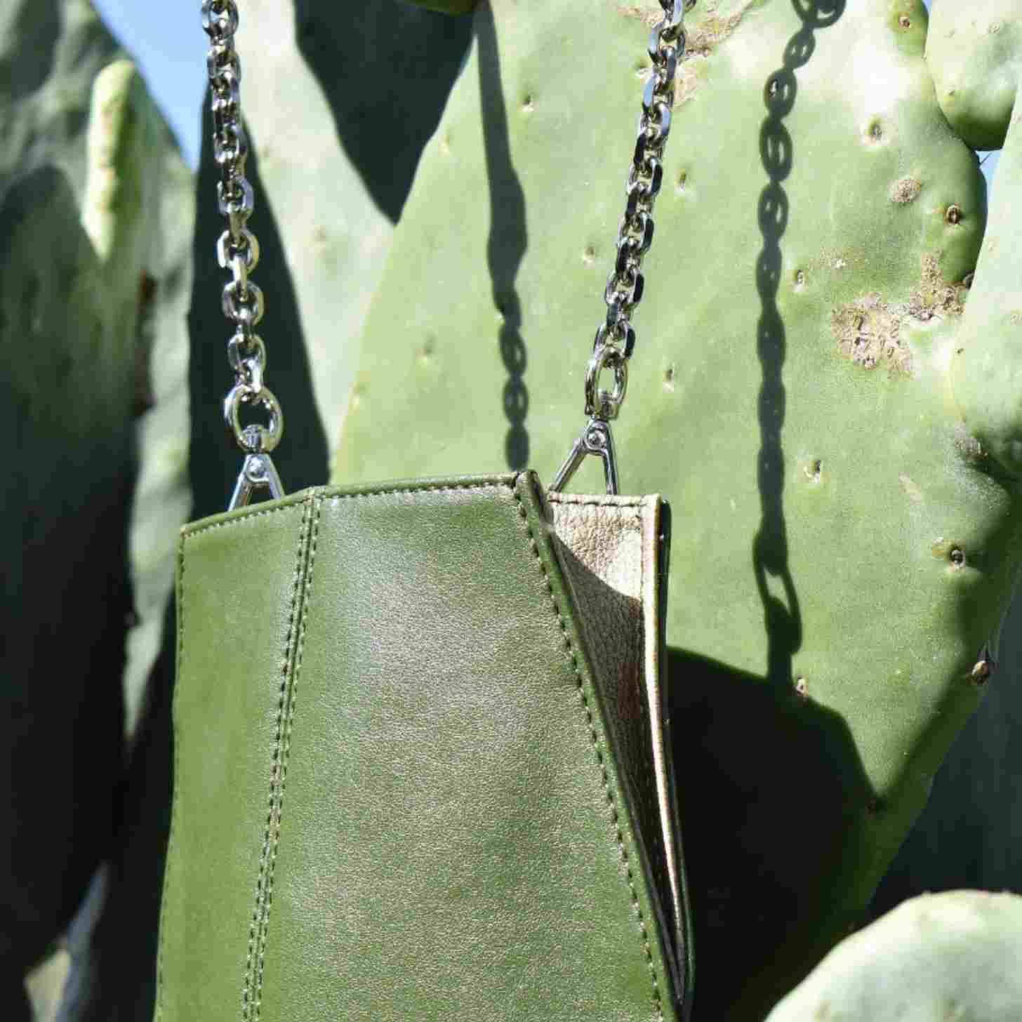 Green leather piece with a silver chain attached to it in front of a cactus