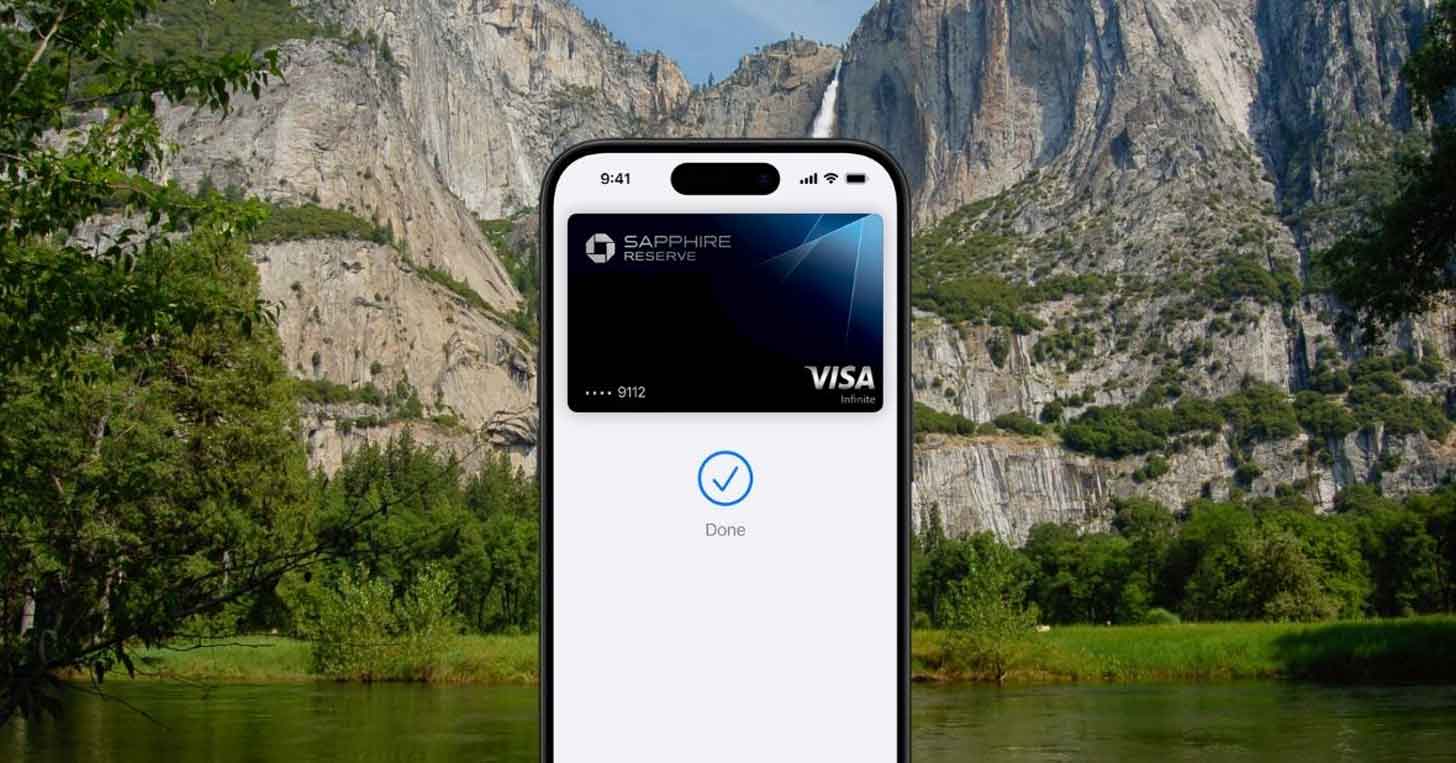 An iPhone with a Visa credit card on the screen and a nature, scenic photo in the background