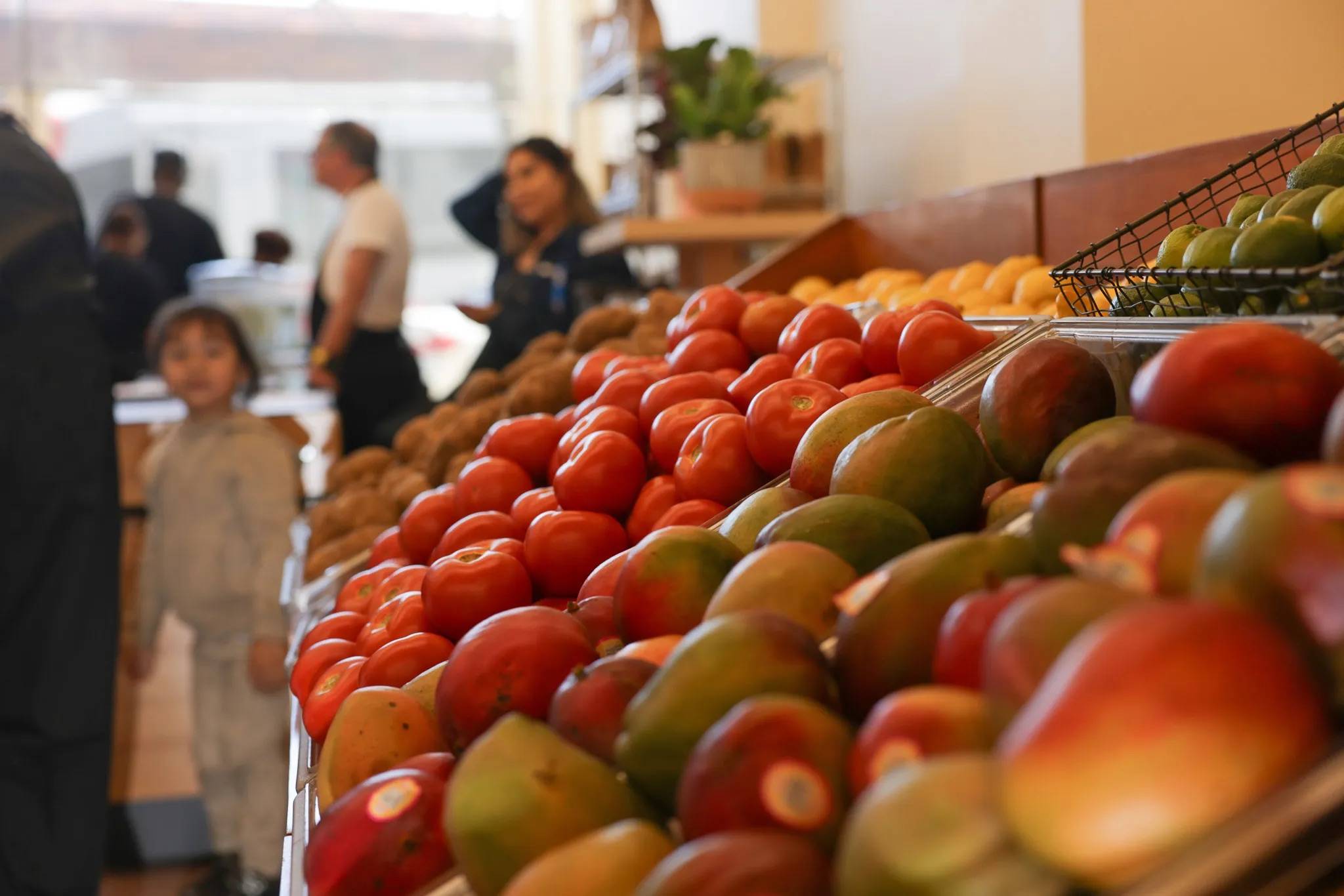 A close-up image of fresh fruit in containers at a grocery store with people blurry in the background