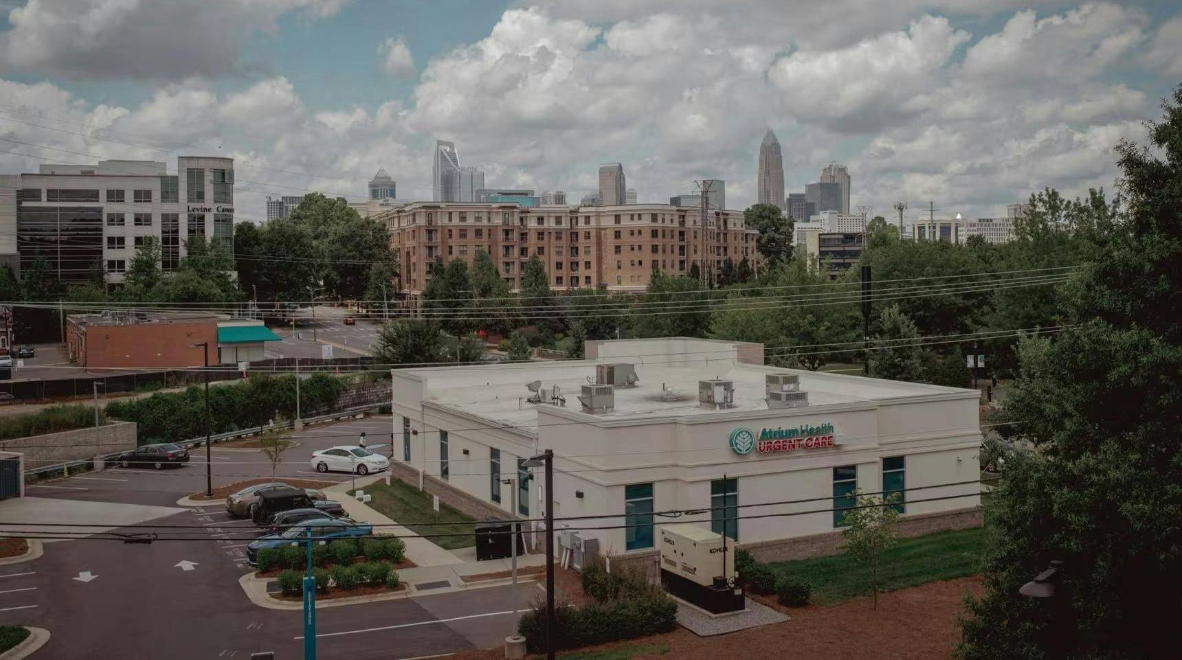Slightly overhead photo of an Atrium Health Urgent Care building with the Charlotte, North Carolina skyline in the distance