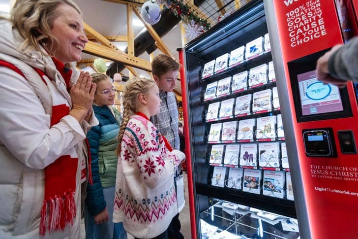 People standing in front of a vending machine filled with cards of items to donate