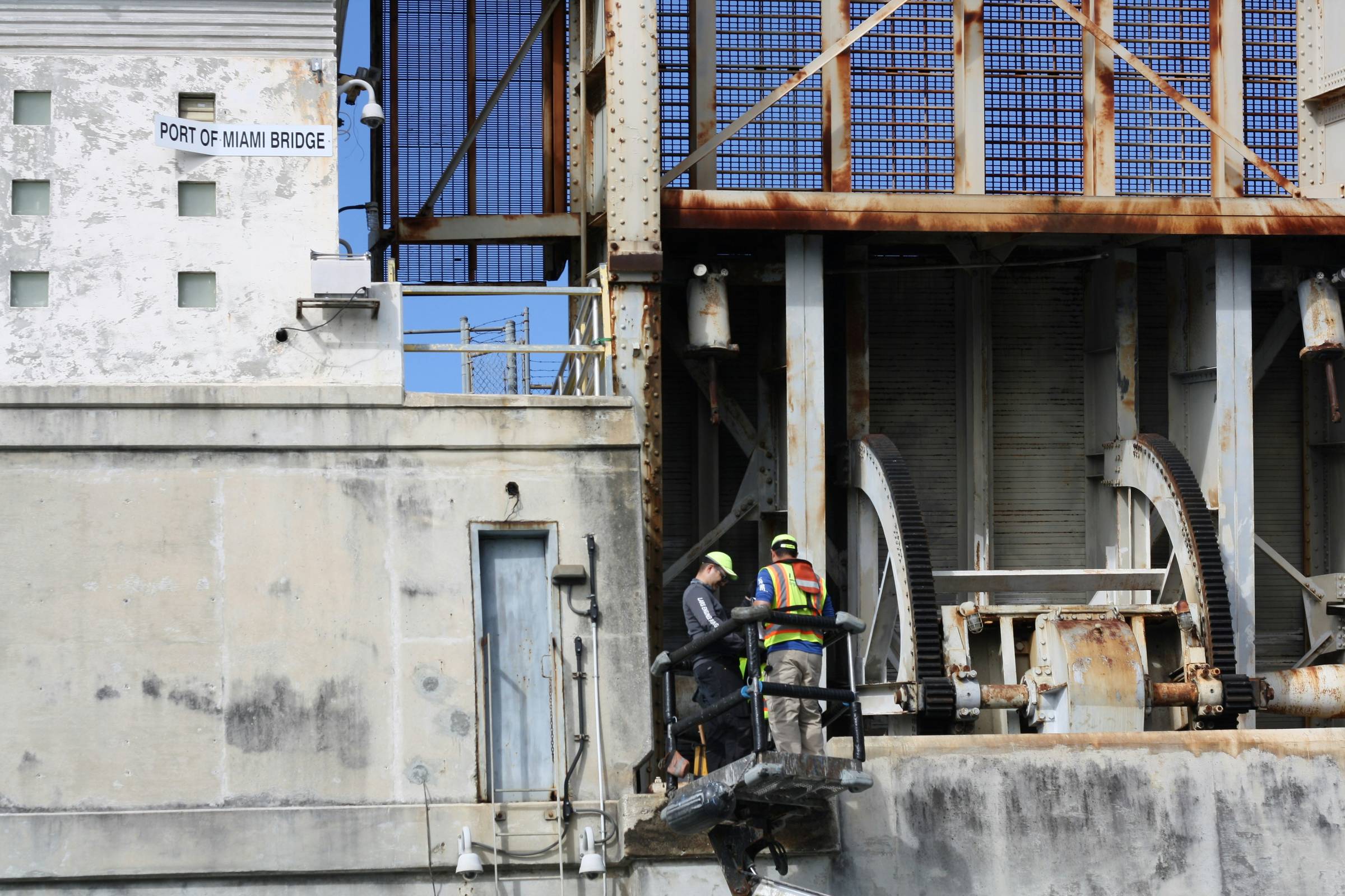 Two construction workers on a lift next to bridge dock