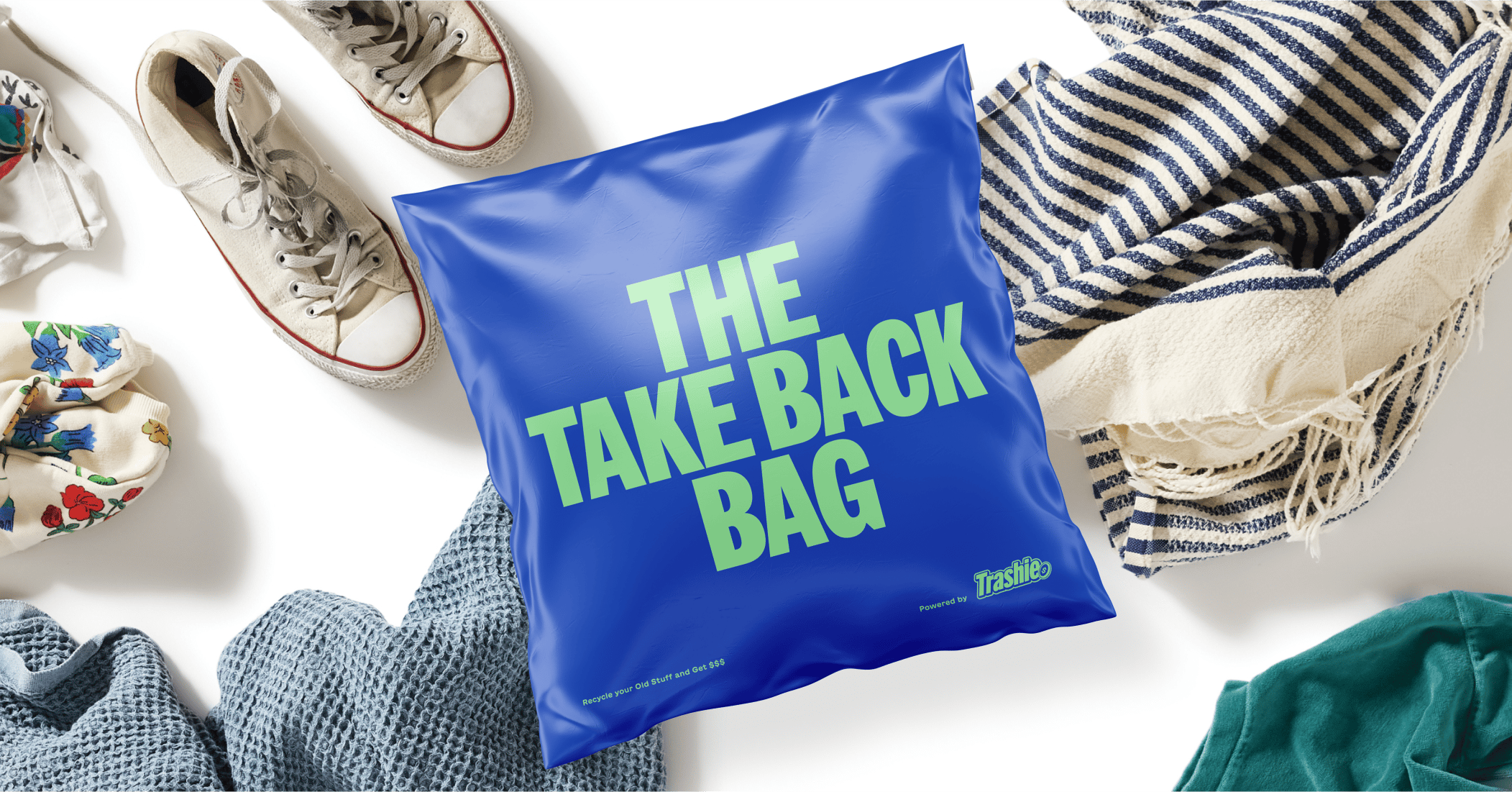 A blue plastic bag with "The Take Back Bag" printed on it in light green on top of shoes, a striped towel, and other fabric items