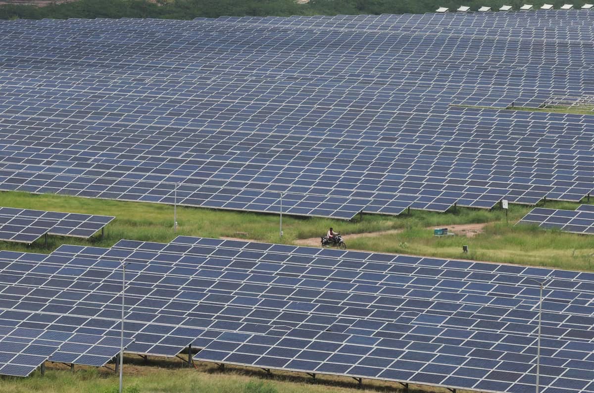 A massive field filled with solar panels, a person is in the middle riding a motorbike