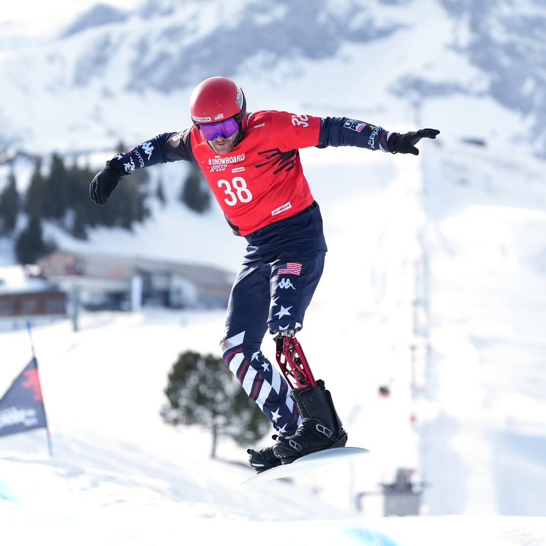 Mike Schultz in full gear snowboarding, his left leg features a prosthetic