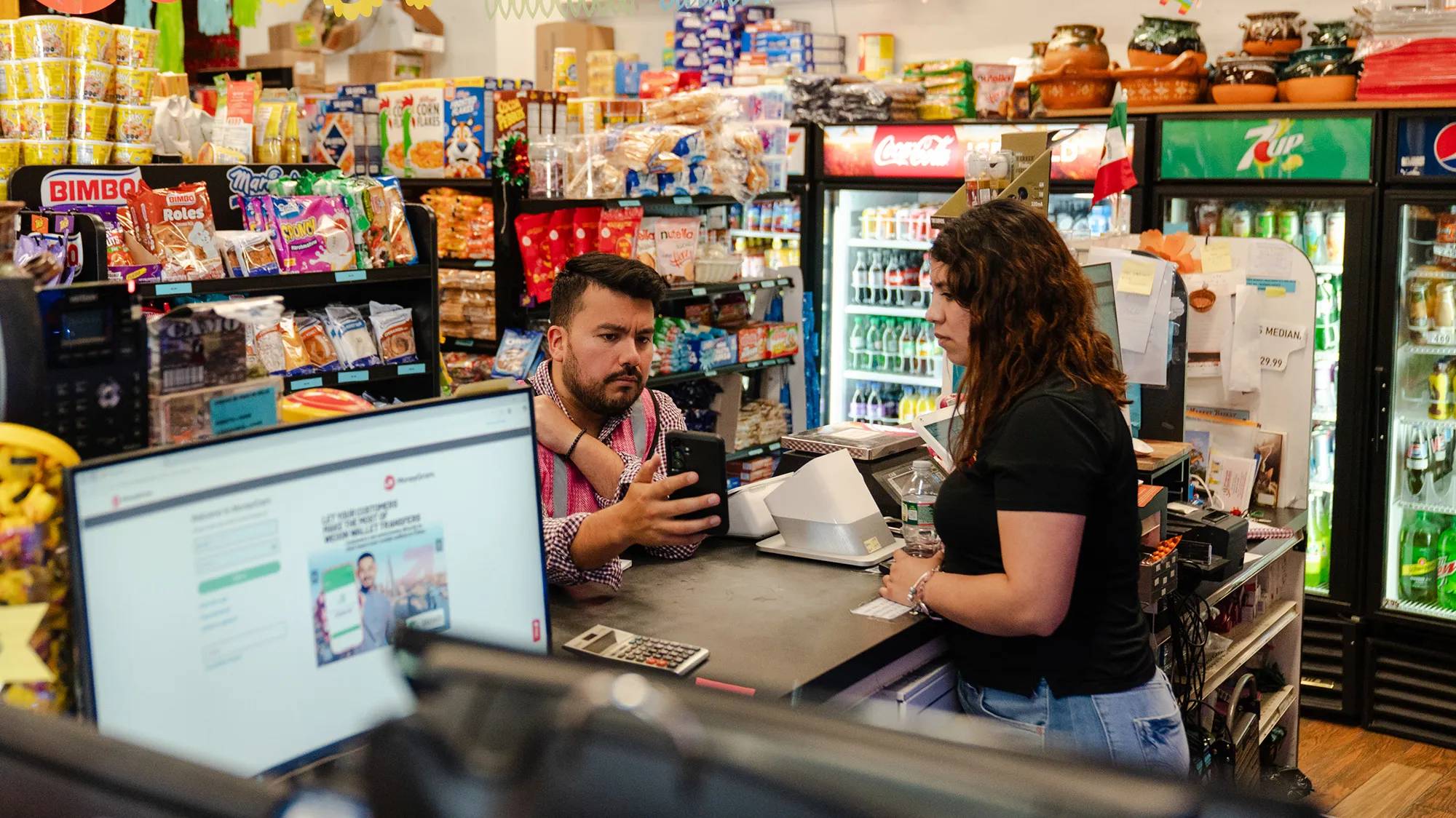 Person showing phone screen to another person behind a checkout counter
