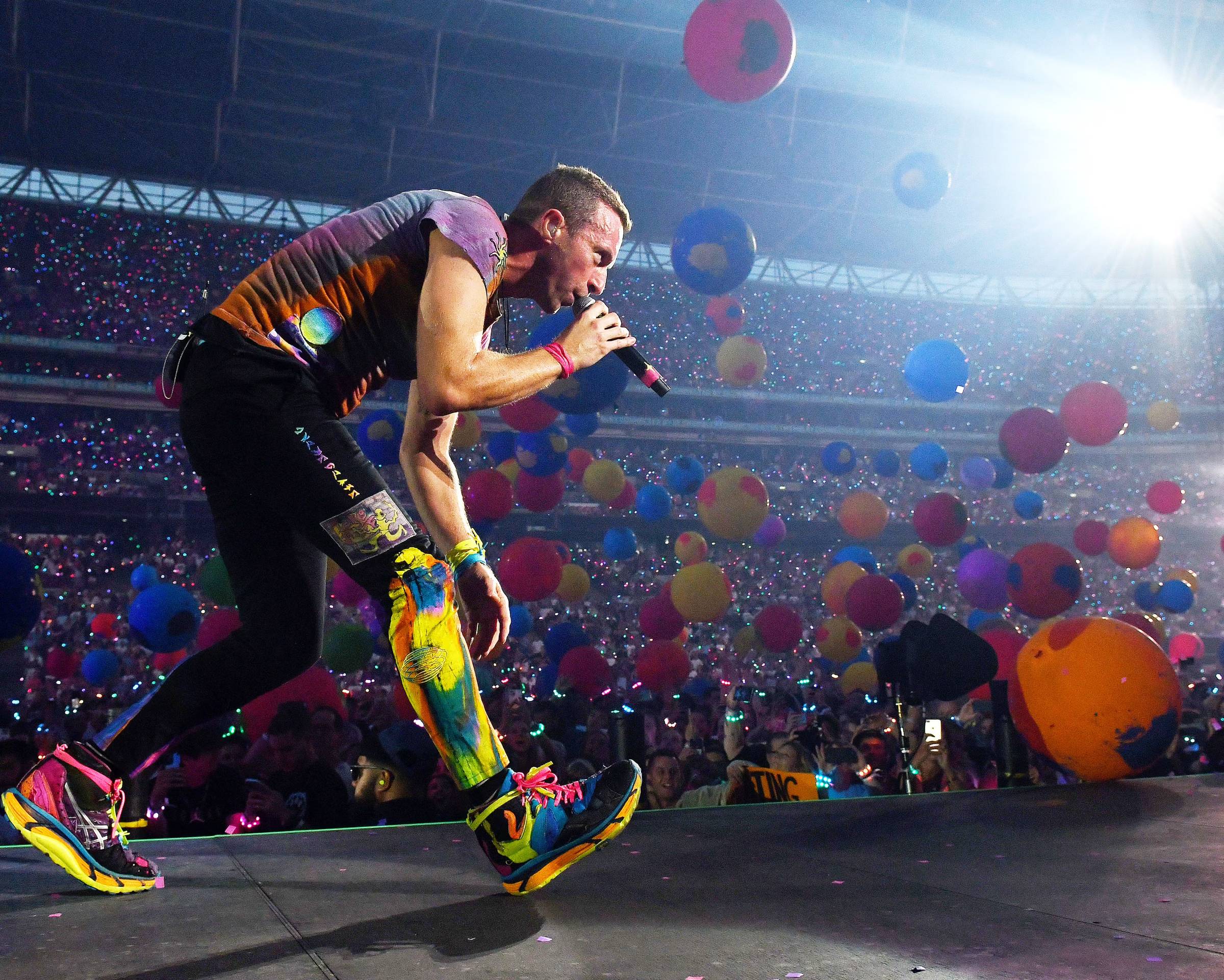 Coldplay's Chris Martin singing into a microphone on stage