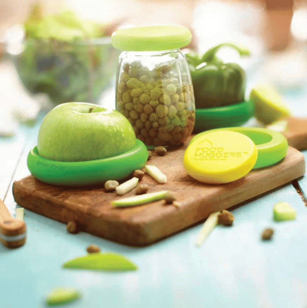 Green and yellow silicone round things covering a cut apple, the top of a jar, a green pepper