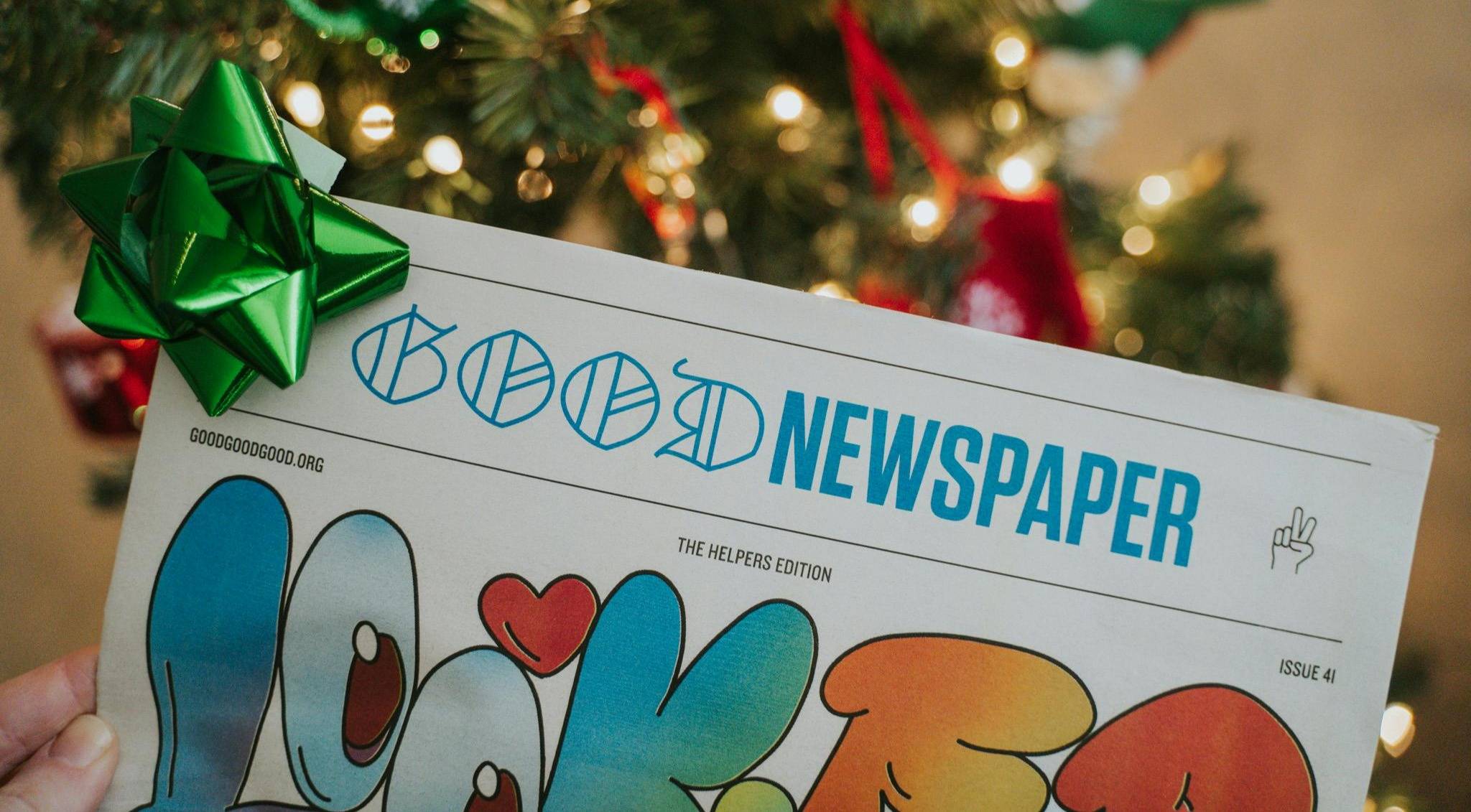 the Goodnewspaper with a green bow on it in front of a tree that's lit up