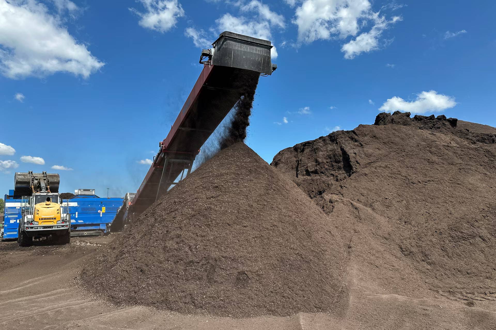 A machine dumping dirt onto a large pile