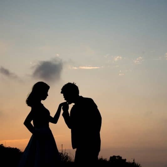 silhouette of man kissing hand of woman