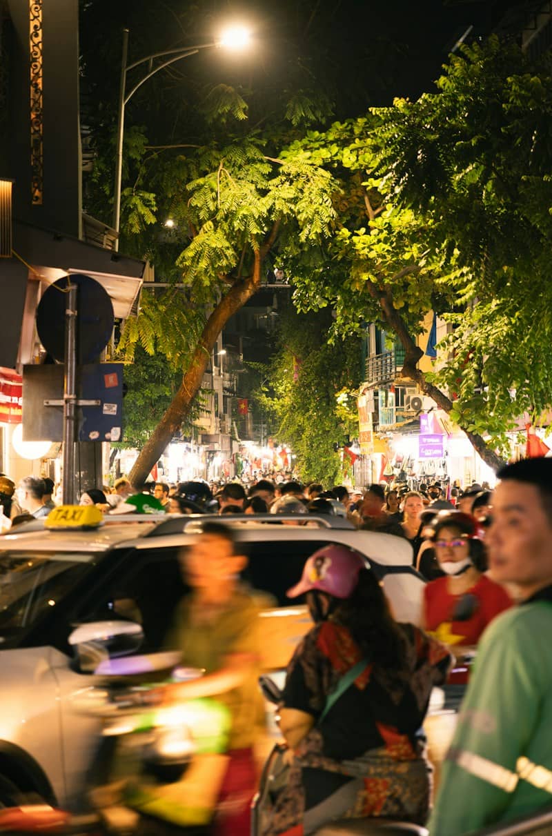 A crowded street at night with blurred traffic and people under streetlights