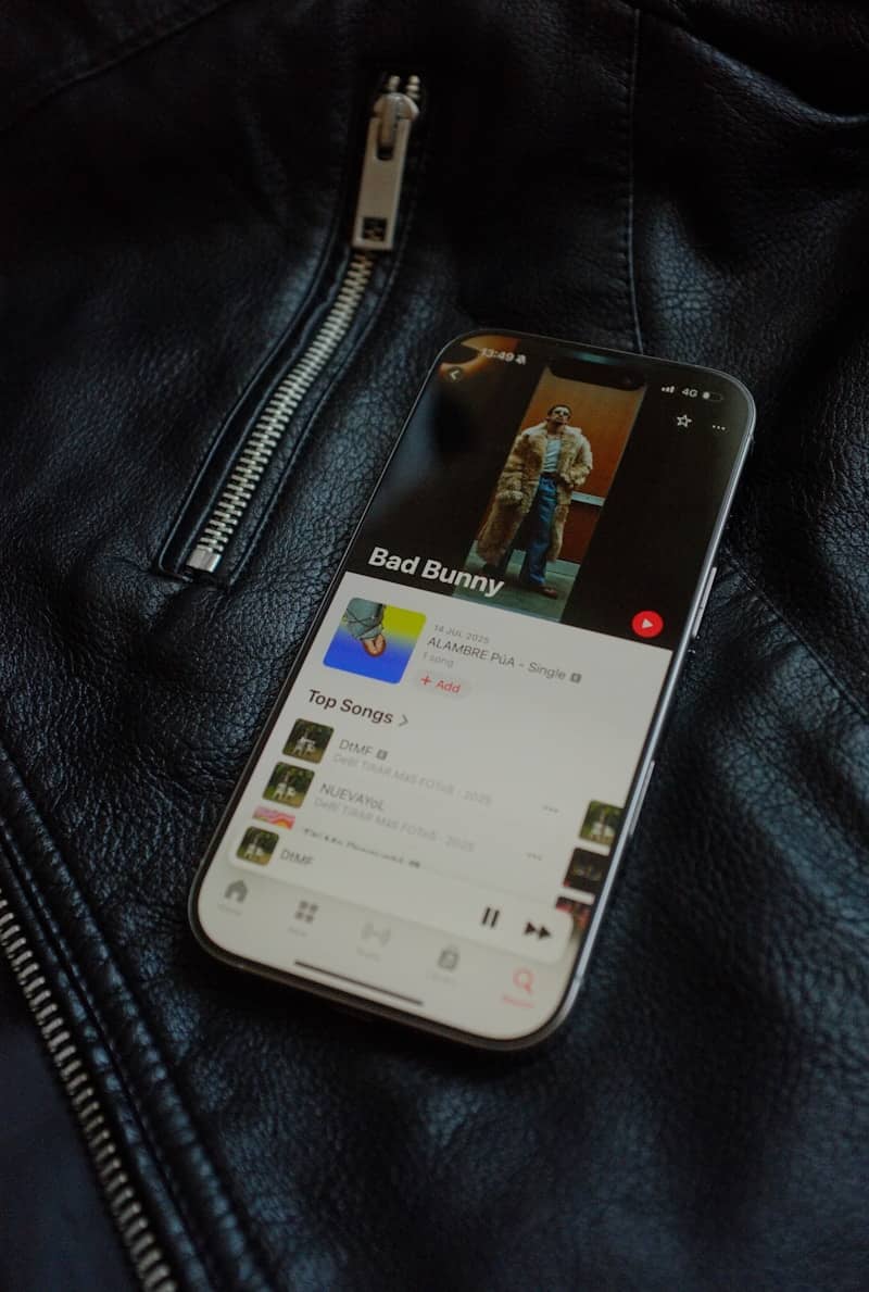 Smartphone displaying bad bunny music on black leather