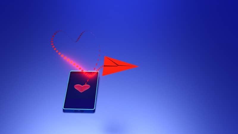 A smartphone sending a red heart with a paper airplane.