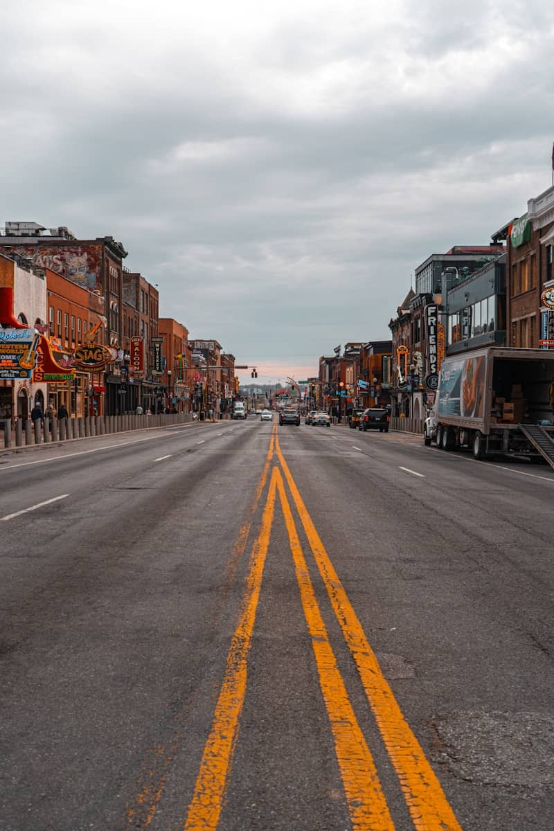 Empty street lined with buildings under a cloudy sky.