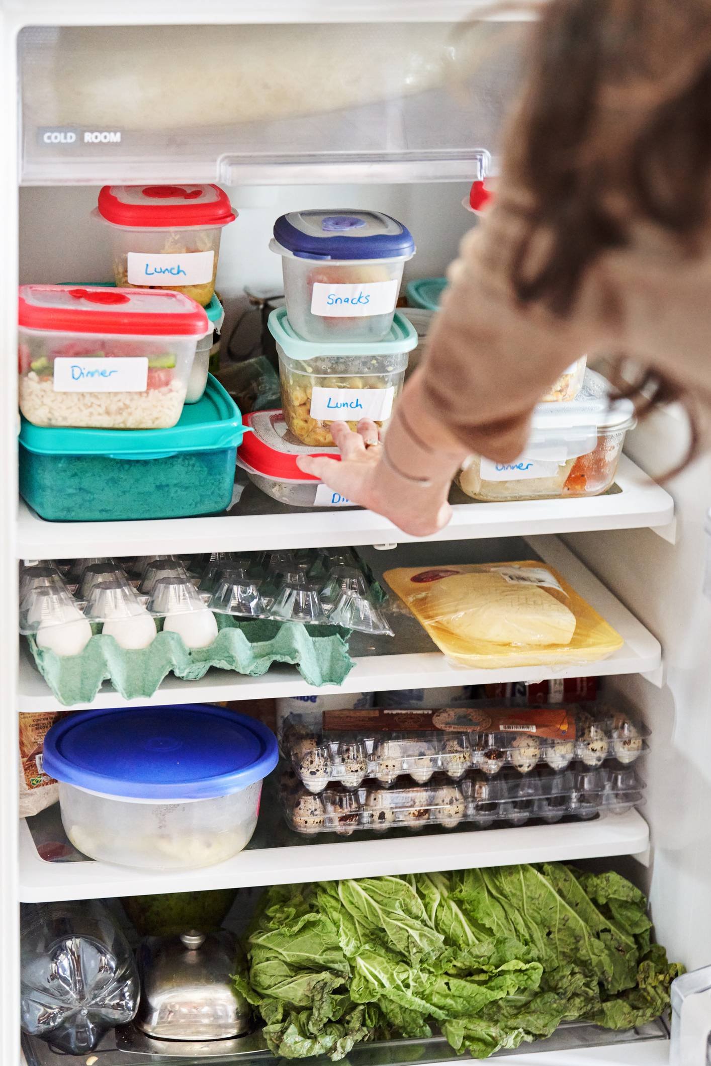Woman looking at prepared meals in the fridge