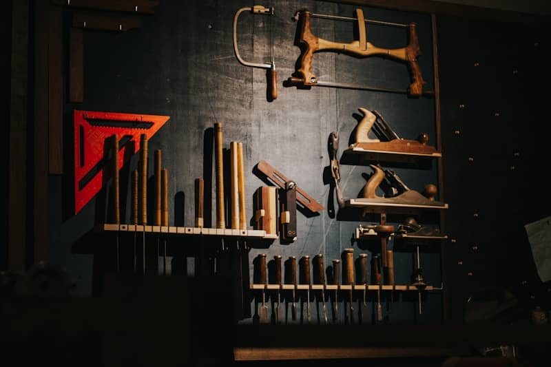 Various woodworking tools hang on a dark wall.